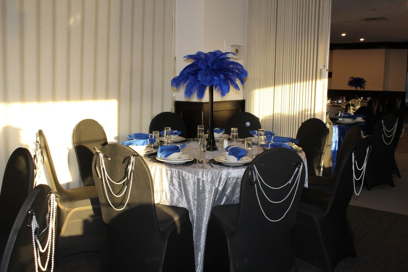 A dramatic blue feather centerpiece with draped pearls on a mitzvah table.