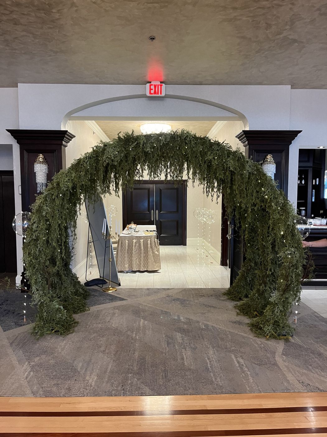 A greenery arch framing a doorway in an elegant ballroom.