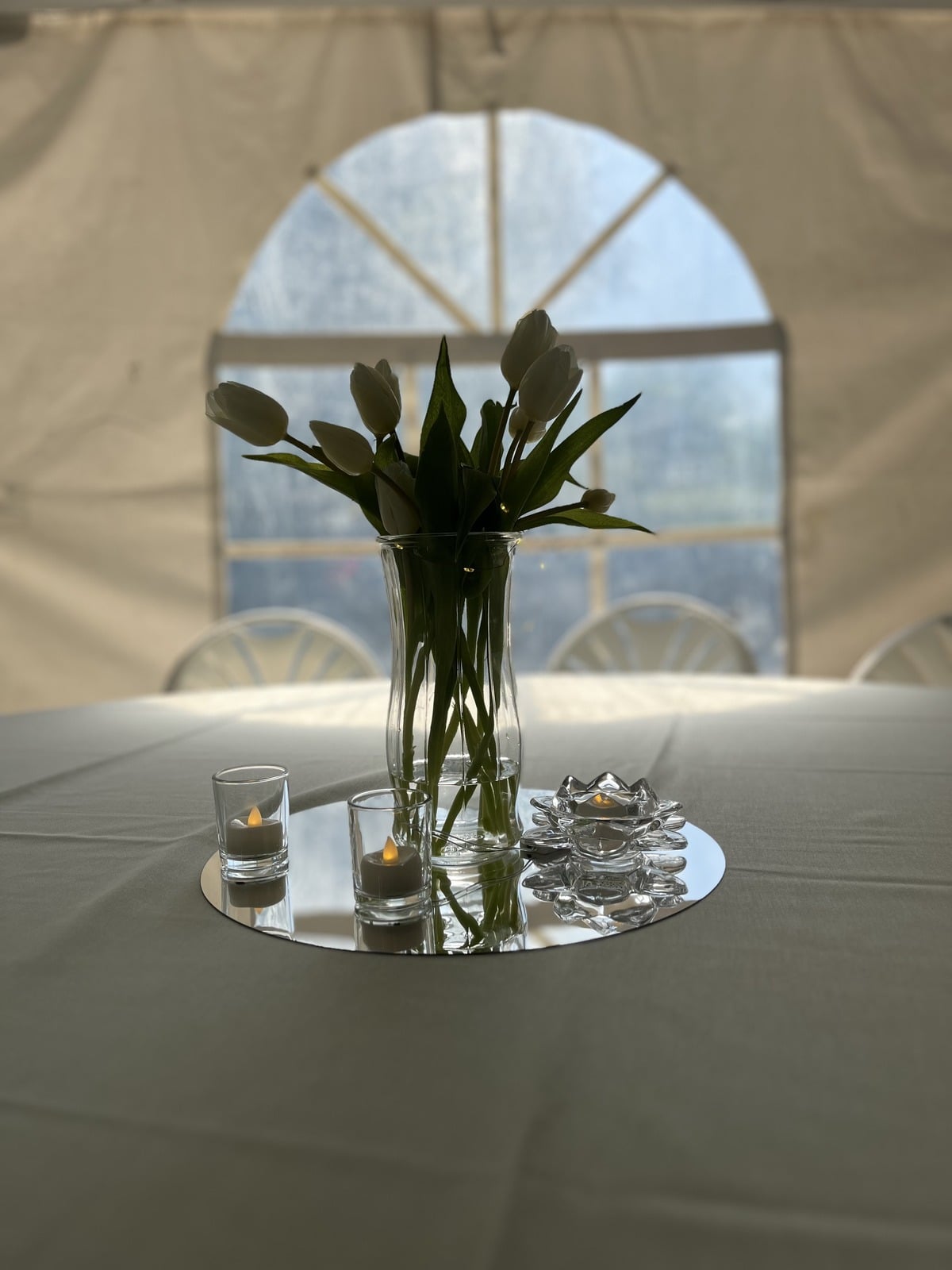 White tulips backlit by a soft arched window at a celebration styled by Weston Events.